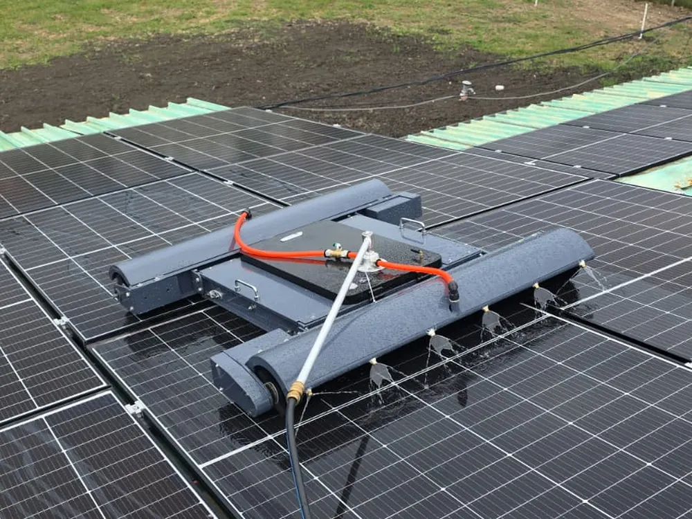 ps hero 1 Acasă - Magazin Online Unilift Serv Robot DUO UnicleanSolar pe acoperișul unei hale, cu rânduri de panouri fotovoltaice și câmpul în fundal
